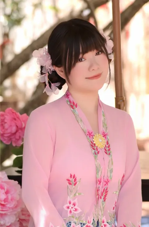 身穿粉色绣花可峇雅、别金胸针的女子站在牡丹花丛前