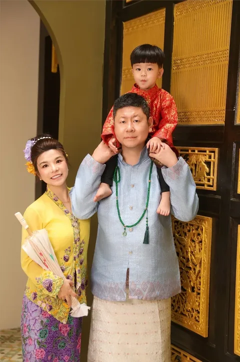 一家三口：母亲着黄色可峇雅，父亲着蓝色峇迪衫，幼儿骑在父亲肩上